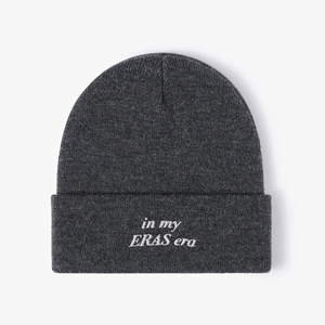 Dark grey knitted beanie with white 'in my ERAS era' embroidery on the cuffed brim
