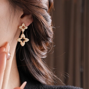 Close-up of gold plated hollow clover earrings with zircons worn by a model