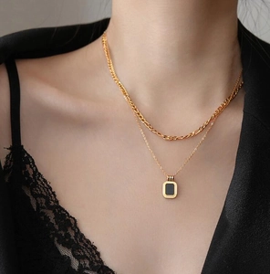 Close-up of double-layered gold necklace featuring a black rectangular pendant on model