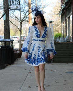 Detail of white deep V-neck dress with blue floral embroidery and lantern sleeves