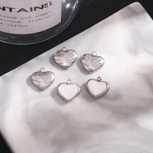 Five heart-shaped stainless steel charms with shell inlay on white marble tray