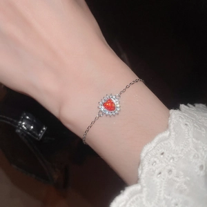 Close-up of heart-shaped red zircon bracelet with white diamond halo on a wrist