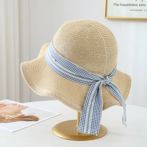 Elegant beige straw hat with blue plaid ribbon bow on a premium gold display stand