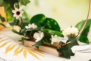 Close-up of floral iron hoop with white flowers and green leaves on a wooden base