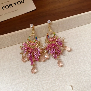 Detail of pink tassel fringe earrings with colorful rhinestones and gold accents