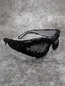 Detail shot of avant-garde black sunglasses with textured lava frame and model specifications
