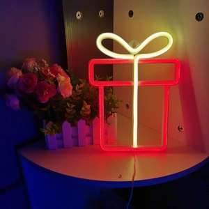 Macro detail of a gift box shaped LED neon sign glowing red with warm white bow light