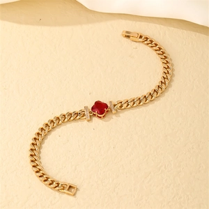 Detail of gold Cuban chain bracelet with red clover gemstone and micro zircon inlays