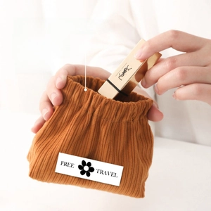 Detail of corduroy pouch with squeeze top spring closure holding a lipstick