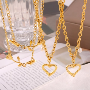 Collier élégant avec pendentif rose dorée, cœur martelé et perle sur fond papier vintage