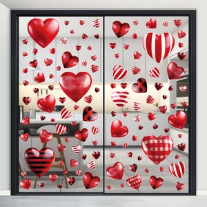 Close-up of red heart window clings with plaid and polka dot patterns on a glass door