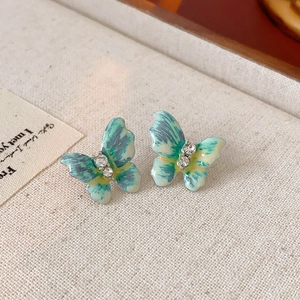 Détail macro de boucles d'oreilles papillon en émail bleu-vert avec cristaux brillants