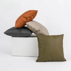 Detailed view of woven checkered plush pillow covers in four earthy colors on pedestals