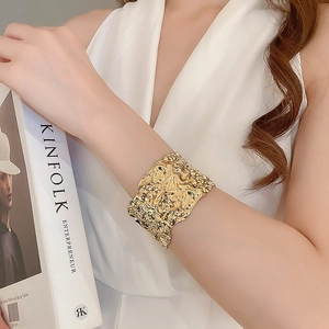 Close-up of golden wide cuff bracelet featuring unique irregular lava texture and folds