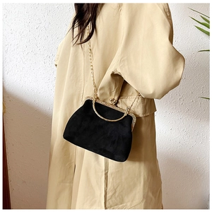 Détail du sac à fermoir en velours noir avec cadre métallique doré et bandoulière en chaîne