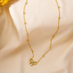 Elegante goldene Titanstahlkette mit hohlem Schleifenanhänger an einer Perlenkette