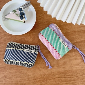 Close-up of woven fabric makeup pouches with contrast stripes and zipper details