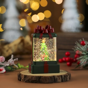 Detail of Christmas gift box snow globe with festive tree inside and red bow