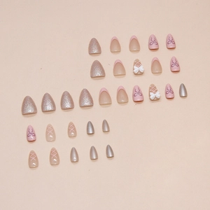 Pink press-on nails with 3D white bows, silver glitter, and ballet ribbon patterns