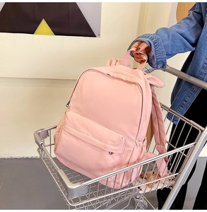 Pink minimalist backpack in a shopping cart featuring dual zippers and side pockets
