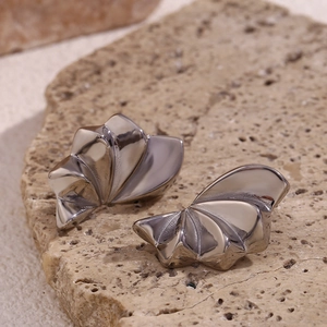 Detail of silver geometric petal earrings with abstract 3D textures on a natural stone base