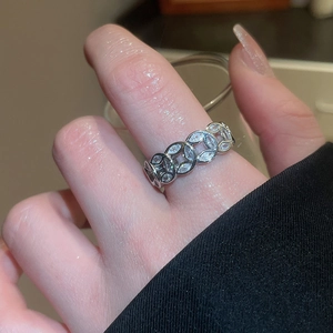 Detailed view of silver open ring with pavé zircons worn on finger in soft indoor lighting
