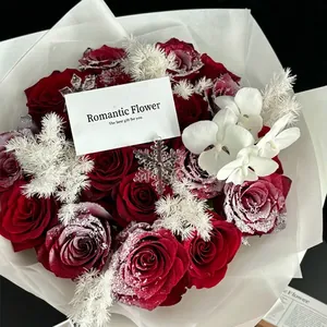 Bouquet di rose rosso scuro con polvere di neve e orchidee in una confezione regalo