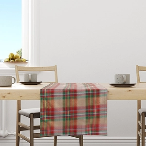 Red and green plaid Christmas table runner on a wooden dining table in a bright room