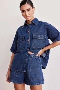 Detail of dark blue denim shirt with large flap pockets and matching high-waist shorts set