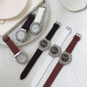 Three quartz watches with silicone straps and rhinestone bezels on a ceramic plate