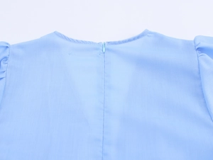 Detail of the light blue dress featuring a hidden back zipper and pleated shoulder seams