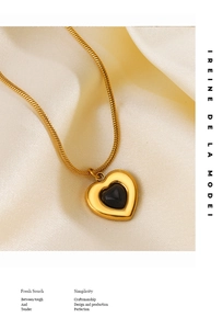 Macro shot of a gold heart pendant with black gemstone on a smooth snake chain