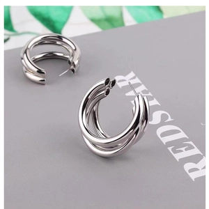 Macro shot of silver triple-layered C-shaped hoop earrings with polished metal finish