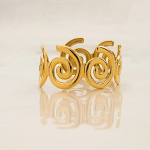Detailed macro view of gold-plated spiral cuff bracelet with polished metal texture