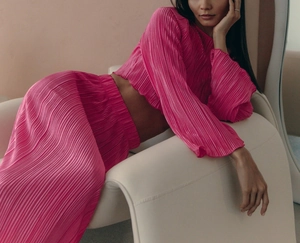 Detail of fuchsia plissé fabric texture on a long sleeve crop top and skirt set