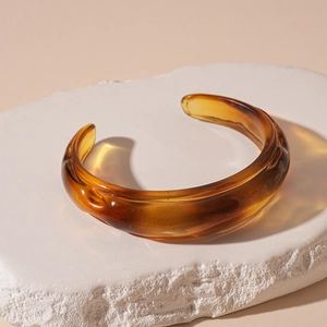 Detailed close-up of amber acrylic resin open bracelet on a natural stone surface
