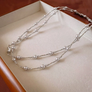 Detail of elegant silver beaded necklace with lobster clasp in a jewelry tray