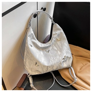 Detail showing silver pleated texture and metal butterfly accents on the tote bag