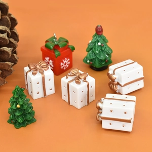 Macro view of miniature Christmas resin gift boxes and tiny trees on orange backdrop