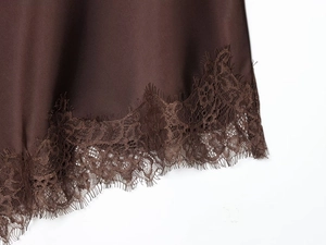 Detail of dark brown satin fabric with delicate eyelash lace trim along the hemline