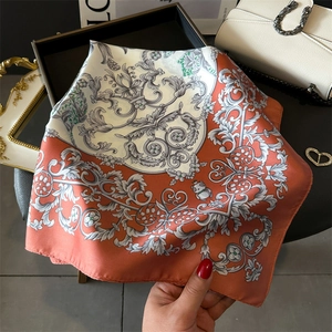 Detailed texture of a floral silk scarf featuring warm orange baroque patterns and panda motif