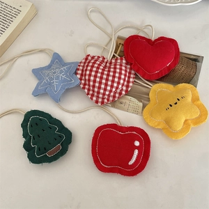 Detail van handgemaakte stoffen hangers met appel-, ster- en hartvormen en witte katoenen koorden