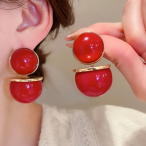 Détail de boucles d'oreilles sphériques rouges avec disque en métal doré sur un mannequin