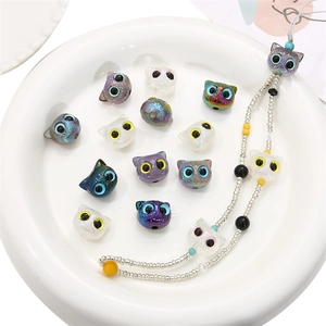 Colorful cat-shaped acrylic beads and handmade beaded phone strap in a ceramic dish