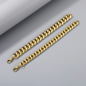 Detail of two golden curb chain necklaces featuring secure lobster clasps on gray backdrop