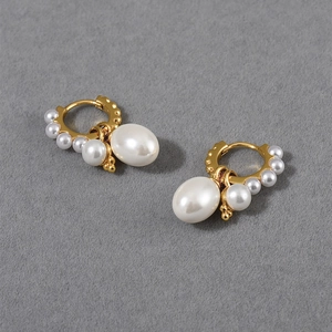 Macro shot of detachable pearl hoop earrings in gold with natural luster on grey background