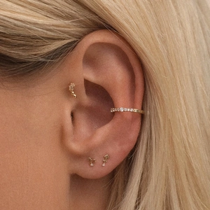 Detail of gold constellation stud earrings and ear cuff set worn by a model