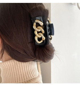 Detail of elegant black hair claw clip with gold chain accent worn on the back of the head