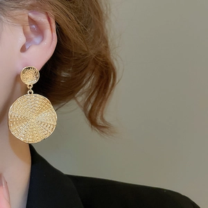 Close-up of gold geometric round drop earrings with hammered texture on model