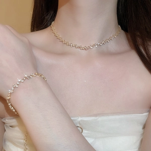 Close-up of gold fringe necklace and bracelet set with sparkling cubic zirconia on model